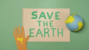 "Save The Earth" with a small world globe and child's hand with a plant for Earth Day 2023.