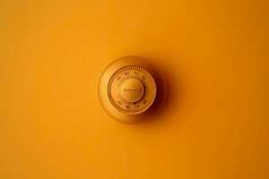 Old-school thermostat with an orange hue over the image.