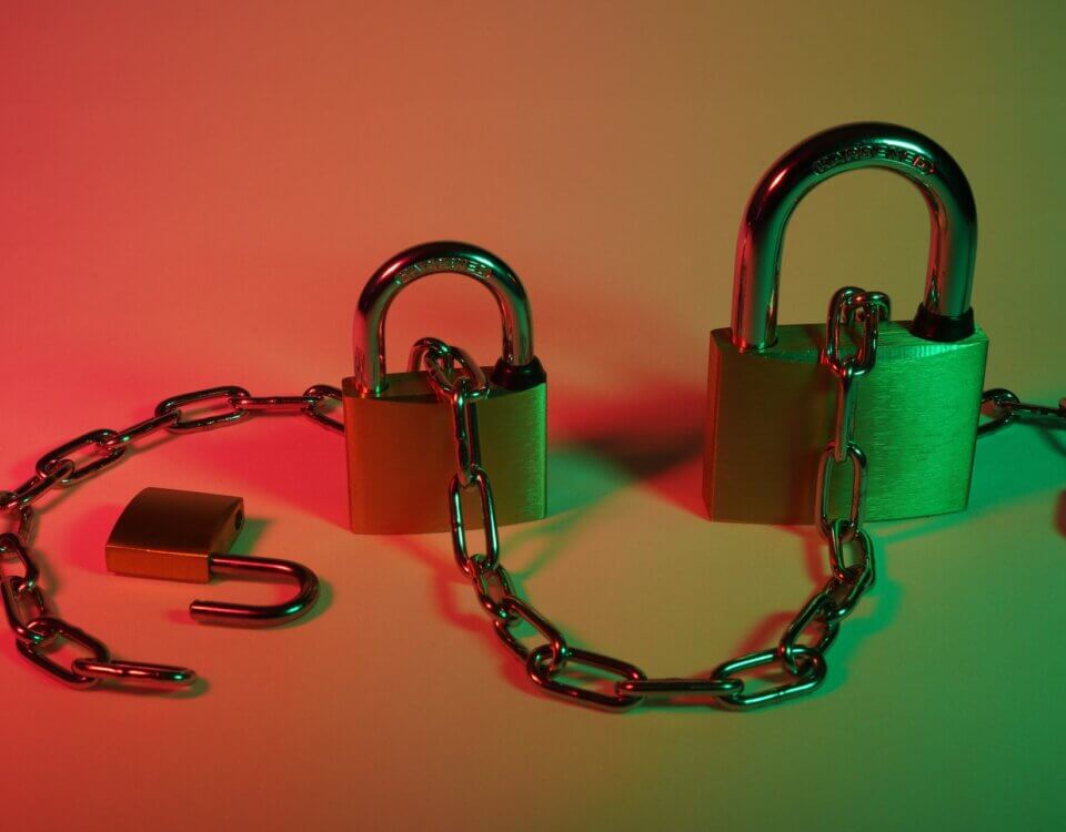 Three different size pad locks with a chain going through them on a red and green background.